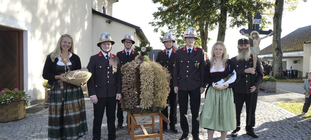 Feuerwehr-Kirtag in Oberösterreich: Jungfeuerwehr und Trachtler mit Erntekrone vor Kirche