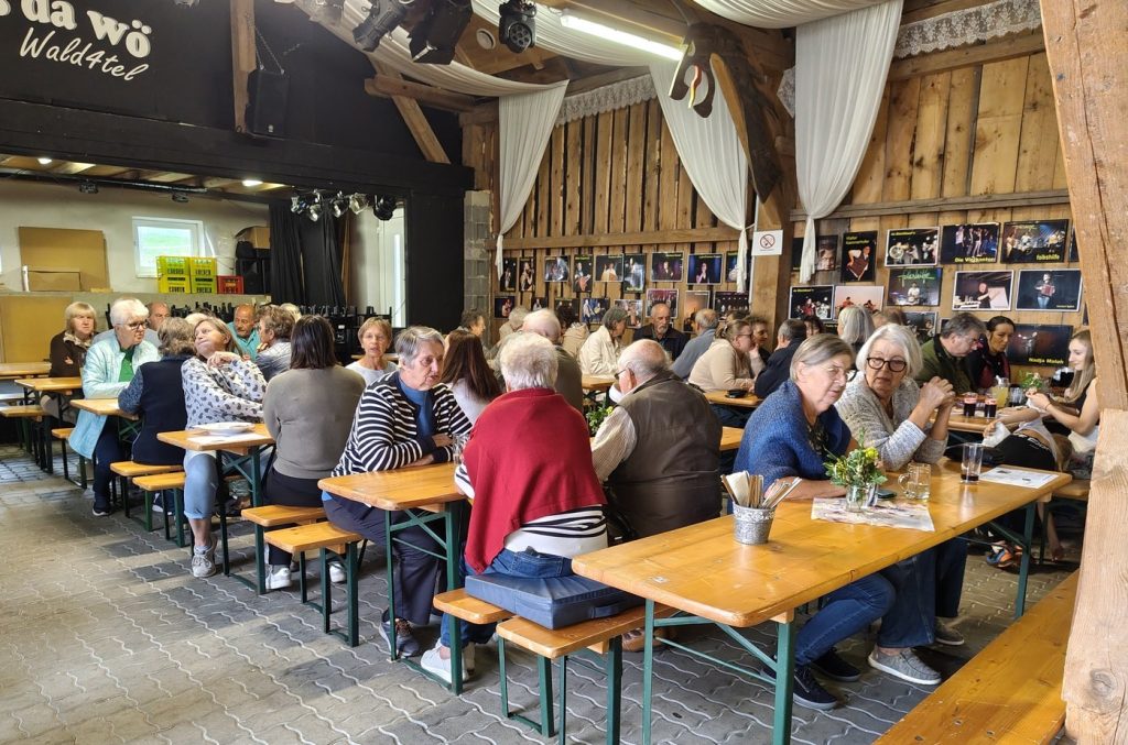 Gäste sitzen an Holztischen in einem rustikalen Gasthaus in Österreich.